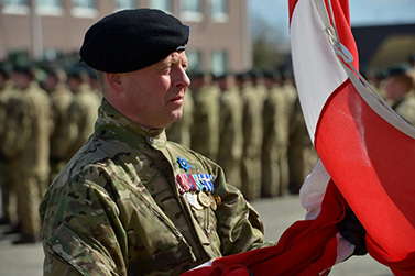 Man in uniform with black beret holding a red and white flag