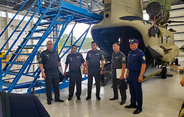 a picture of five man in uniform standing in front of an aircraft