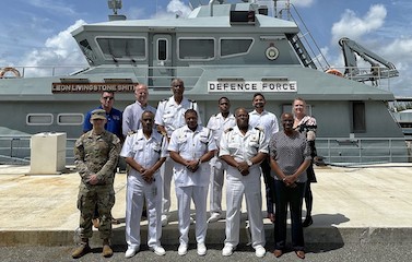 A picture of the participants standing in front of the Defense Force ship