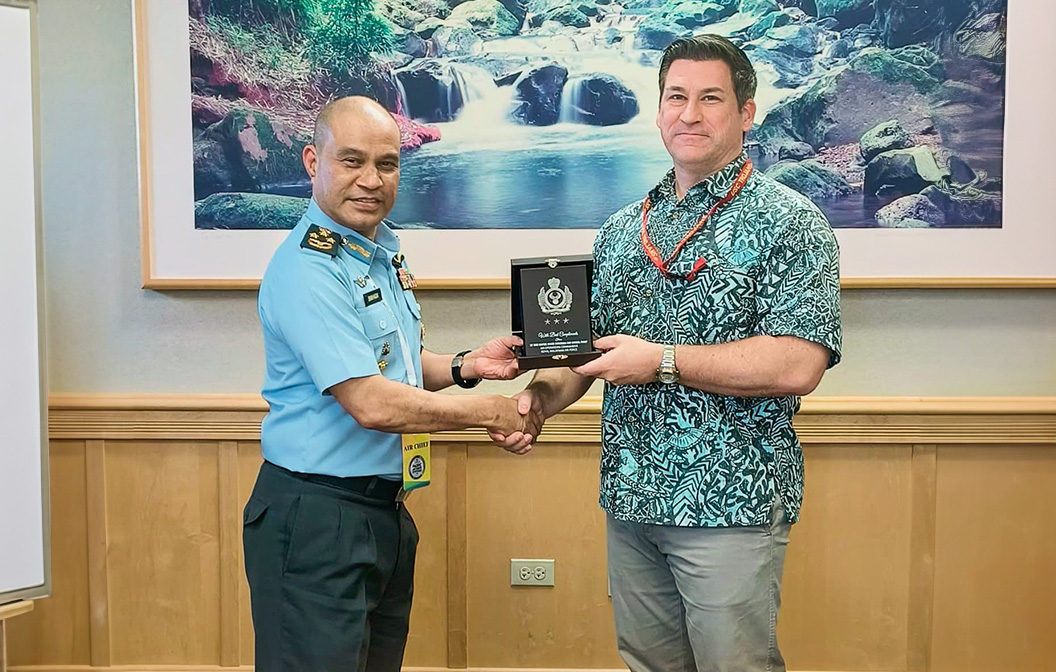 A picture of a man in a Hawaiian shirt shaking hand with the uniformed Air Chief 