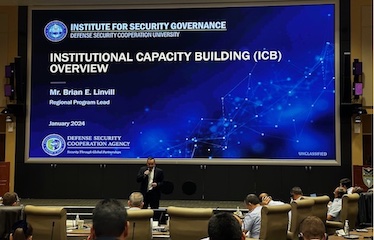 a picture of a man in a black suit speaking at a conference