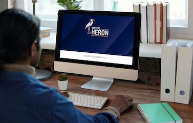 graphic of a person viewing the heron issue on a desktop