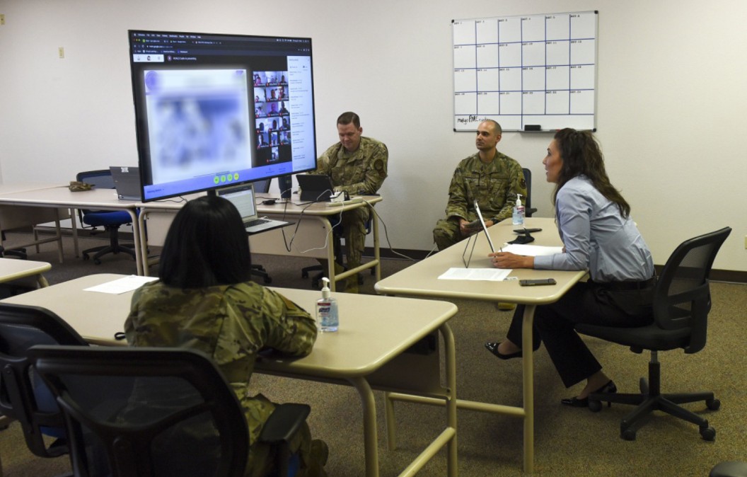 Two women and a man sitting down, facing a screen, conducting virtual education 