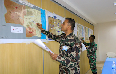 a picture of a man in military uniform pointing his pen at a map on the wall