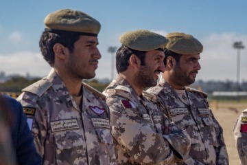 A picture of three men, who are part of the Qatar Armed Forces, looking into a distance