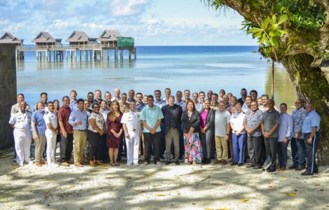 ISG personnel standing alongside with the Palauan delegation in front of a beautiful beach in Koror Palau