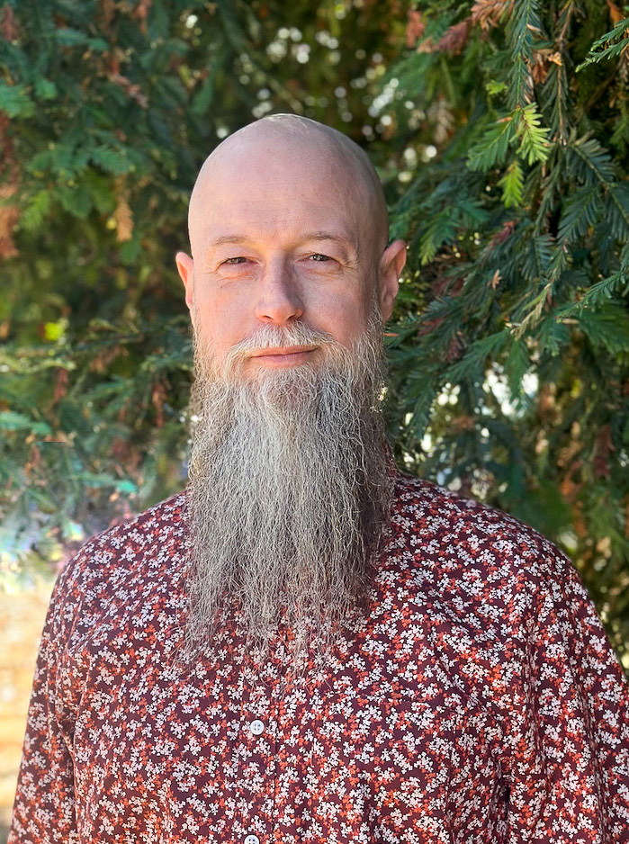 white man in glasses with a long white beard in red patterned shirt