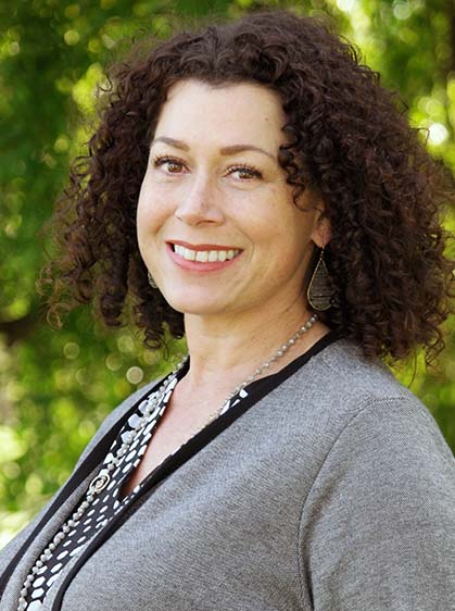 A picture of a woman with curly hair wearing a grey cardigan