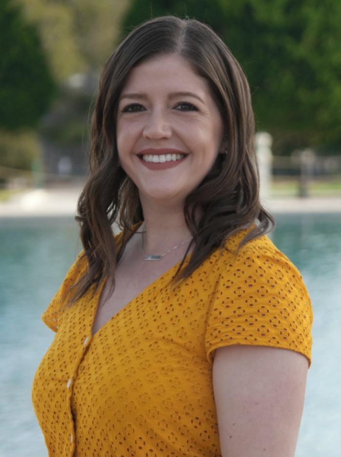 chloe standing in front of reflecting pool wearing a yellow blouse