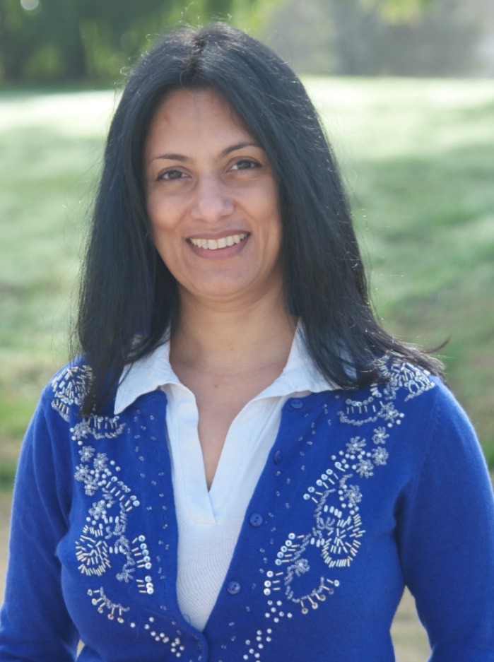 A portrait of a woman wearing a power blue cardigan with a white shirt underneath