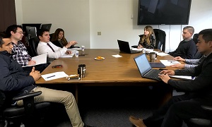 Eight participants sitting at a table in discussion