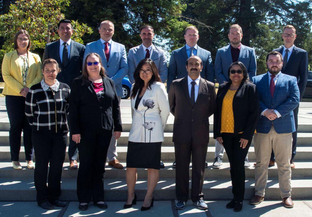 group of people in formal attires standing in front of beautiful green trees