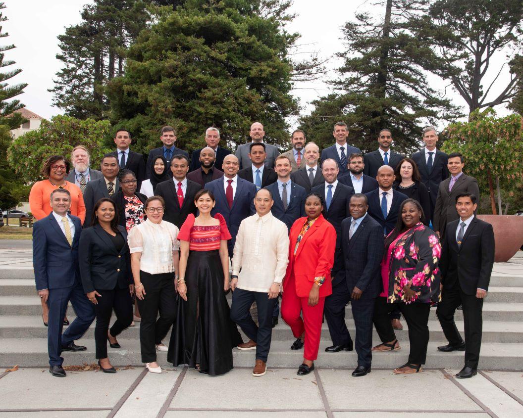 group of people in formal attires standing in front of beautiful green trees